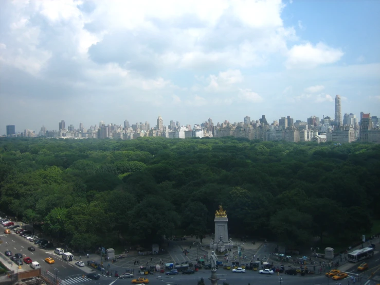 a park with cars, buildings, and other high rises in the distance