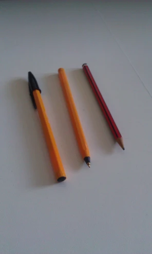 three pencils sitting on a white surface with one end broken