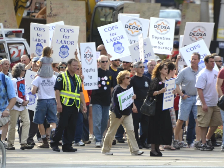 several people on the street holding signs and carrying umbrellas