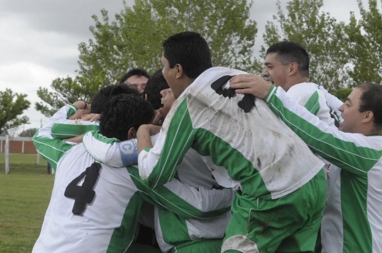 a group of young men hug while playing soccer