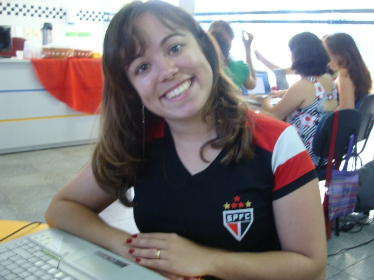 a young woman is smiling as she uses her laptop