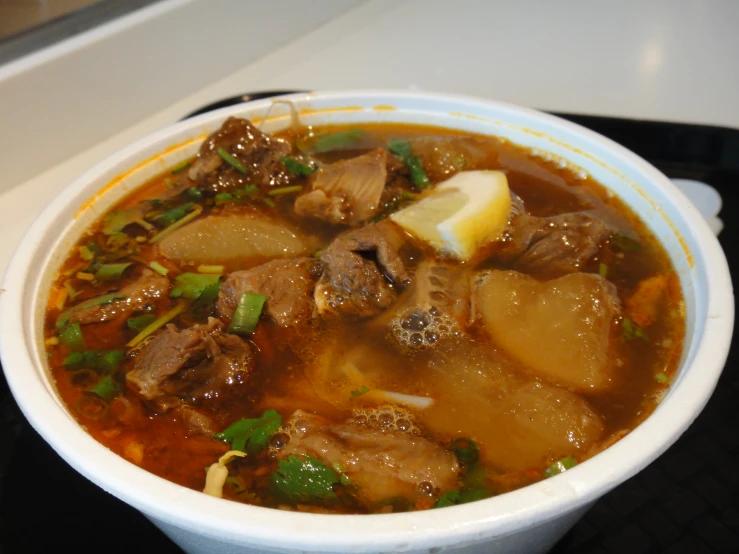 a white bowl filled with meat and vegetable soup