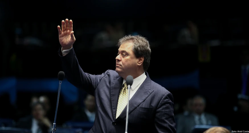 a man in a suit is waving his hand up