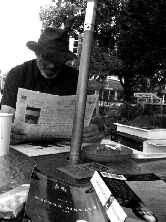 a person is sitting at a table reading newspapers