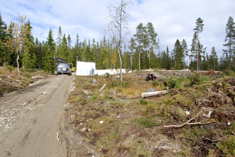 a truck is on a dirt road next to trees