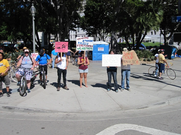 people standing outside holding up signs and riding bikes