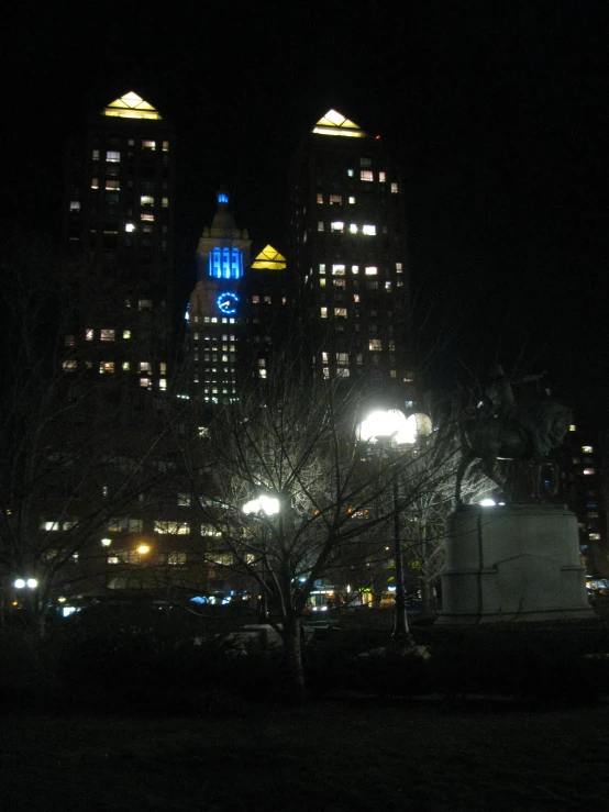 buildings lit up at night in front of a large clock tower