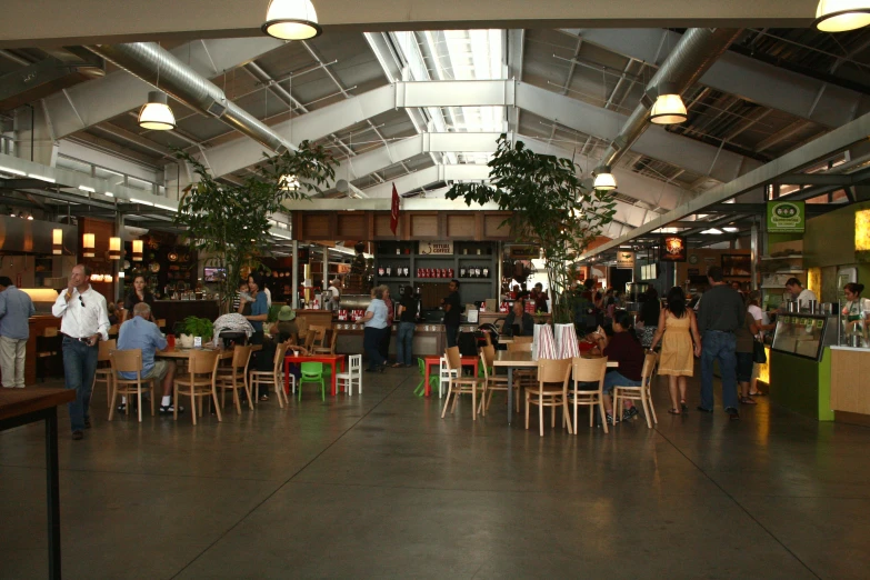 people are sitting and standing inside of an industrial restaurant