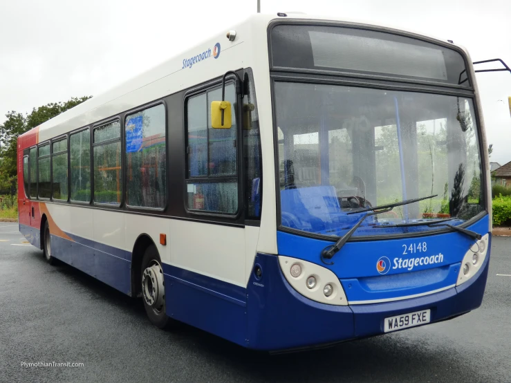 blue and white bus parked on the road near a parking lot