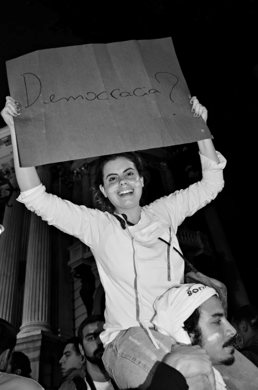 an excited girl holds a sign in front of a crowd