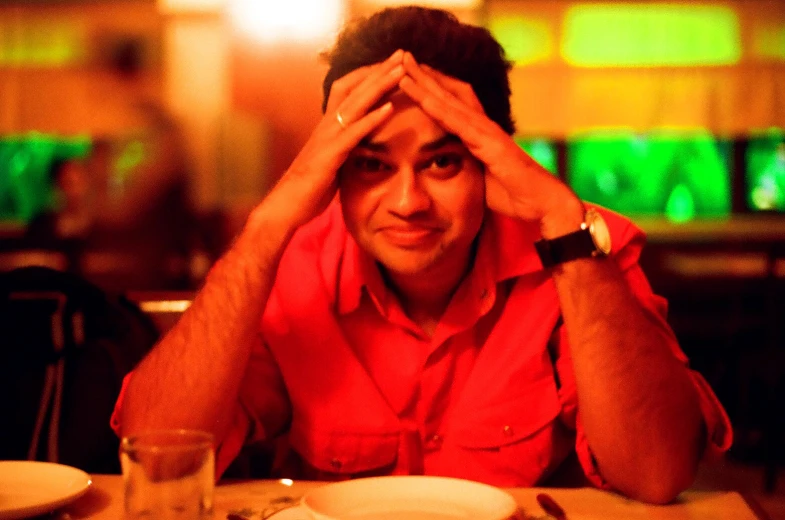 a man sitting at a table holding his head