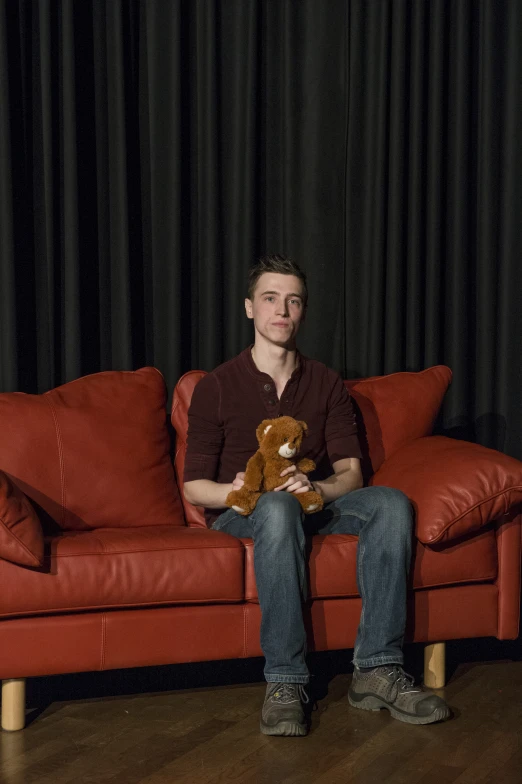 a man sitting on a couch holding a teddy bear