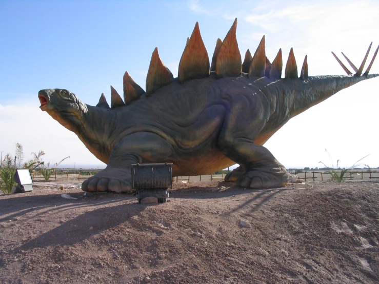 the statue of a large dinosaur sits in the dirt