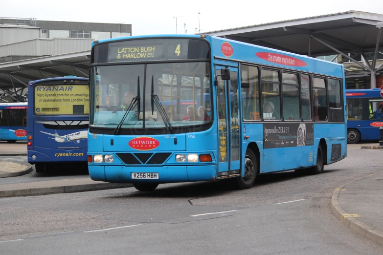 two blue busses side by side, one has no passengers