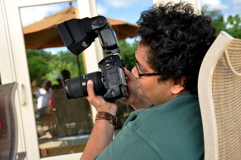 a man sitting in front of a chair holding a camera