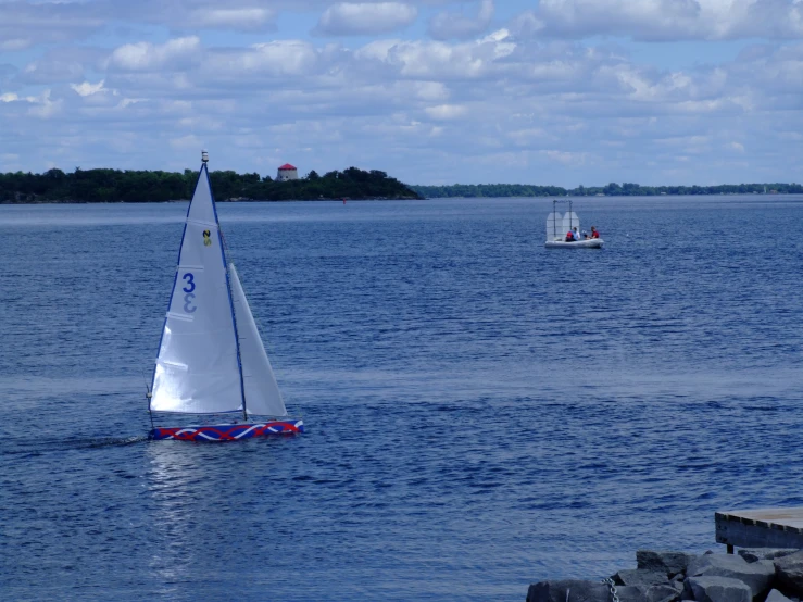 a sailboat on the water near some rocks