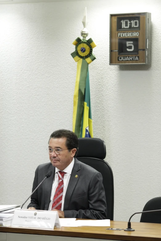 a man sits at a table in front of a clock