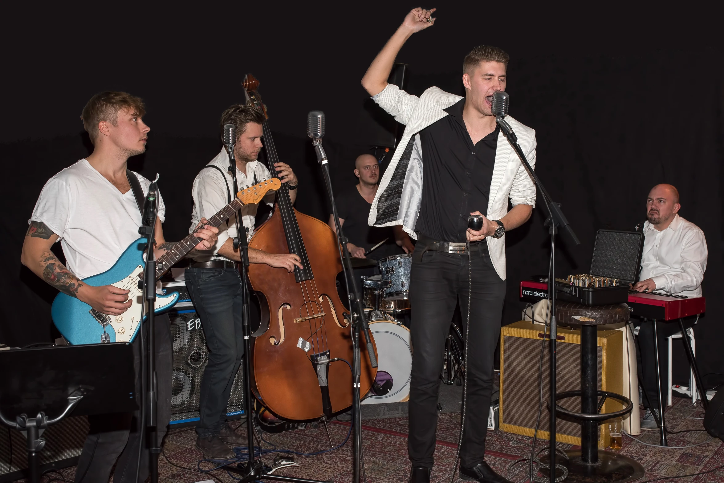 men in black and white outfits are playing music on guitar