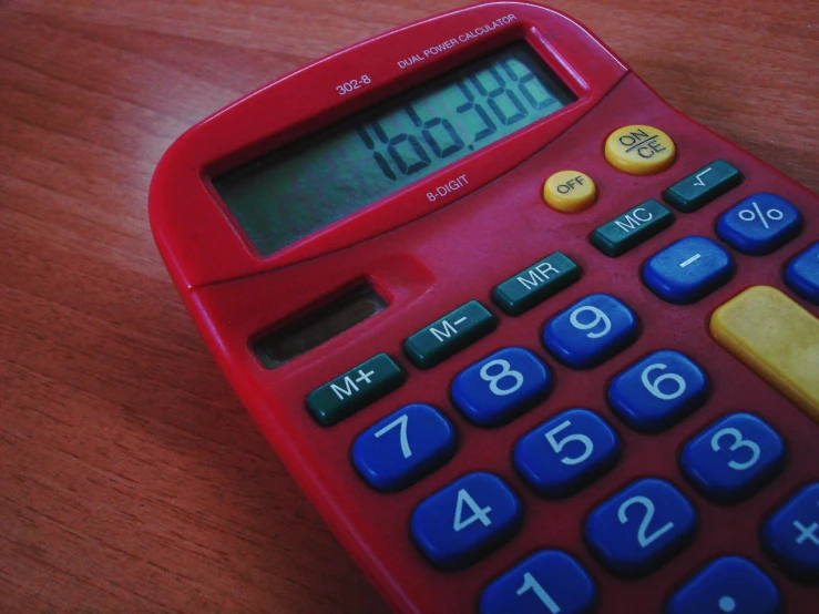 a red calculator sitting on a wooden table