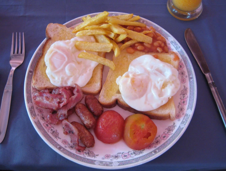 a plate filled with eggs, meats, fries and fruit