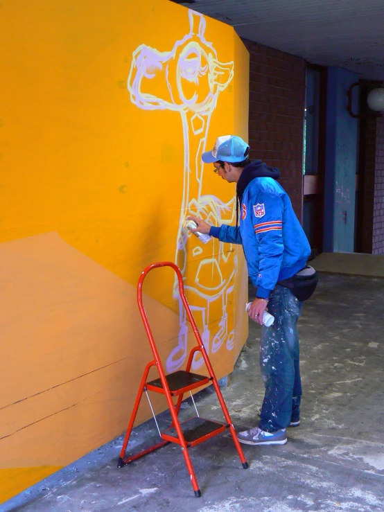the man is painting the wall with yellow and white art