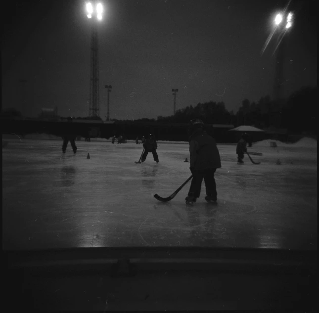 several people playing hockey on an ice rink at night