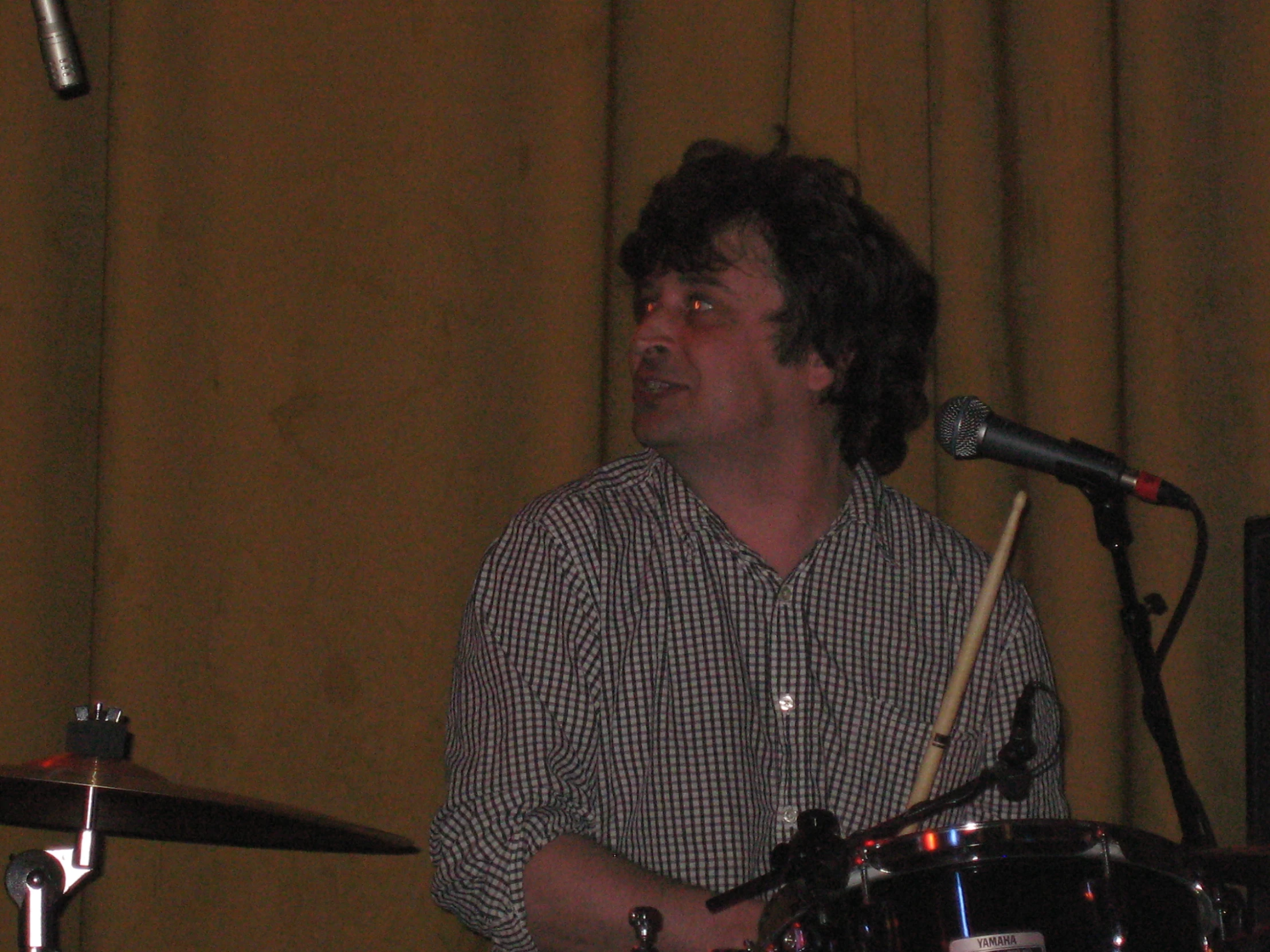 a man is playing the drums while a microphone stands behind him