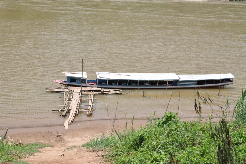 a long boat sits parked on the water with no people