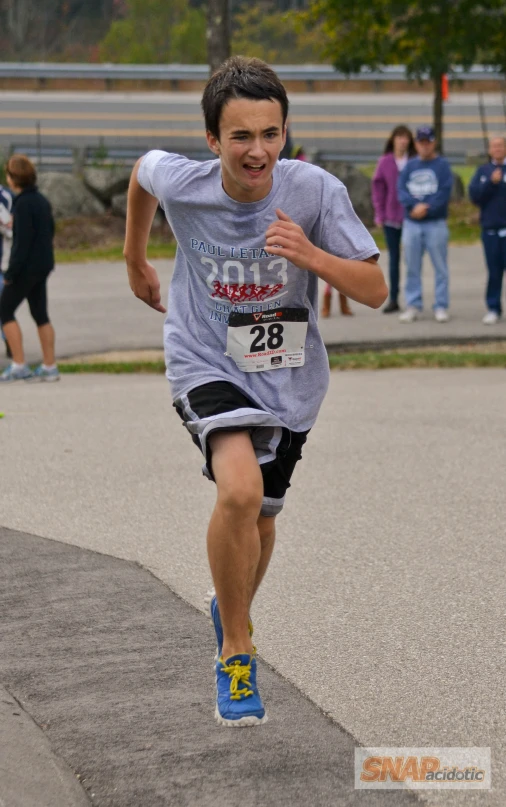 a boy running in a race while others watch