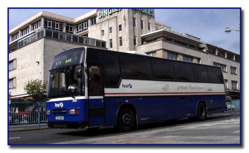 a blue, white and red bus driving through an area