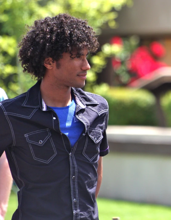 a black man walking through a park on a sunny day