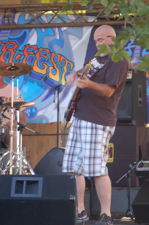 a man with a guitar standing in front of a stage