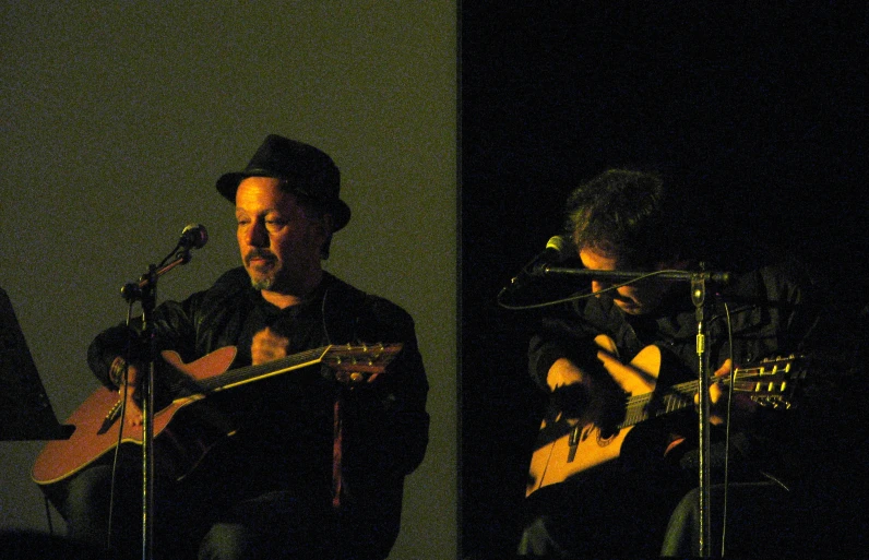 a man standing next to a microphone and playing a guitar