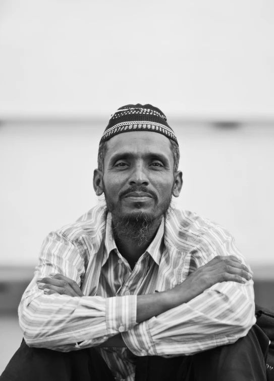 a man sitting on a stool with his arms crossed