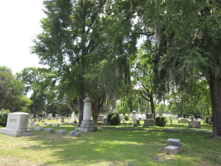 an empty cemetery with tombstones and trees on the lawn