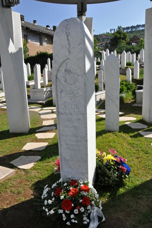 an outdoor memorial with a circular white stone structure behind flowers