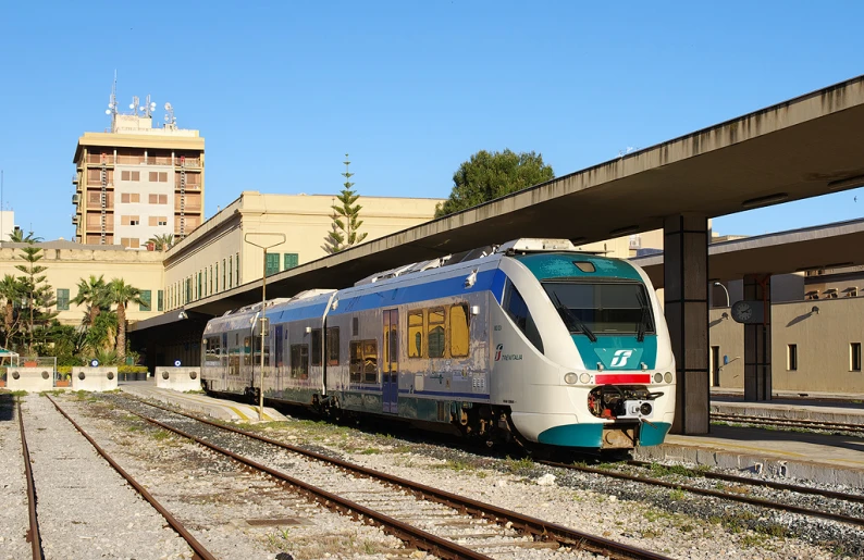 a train stopped at the platform with building in background