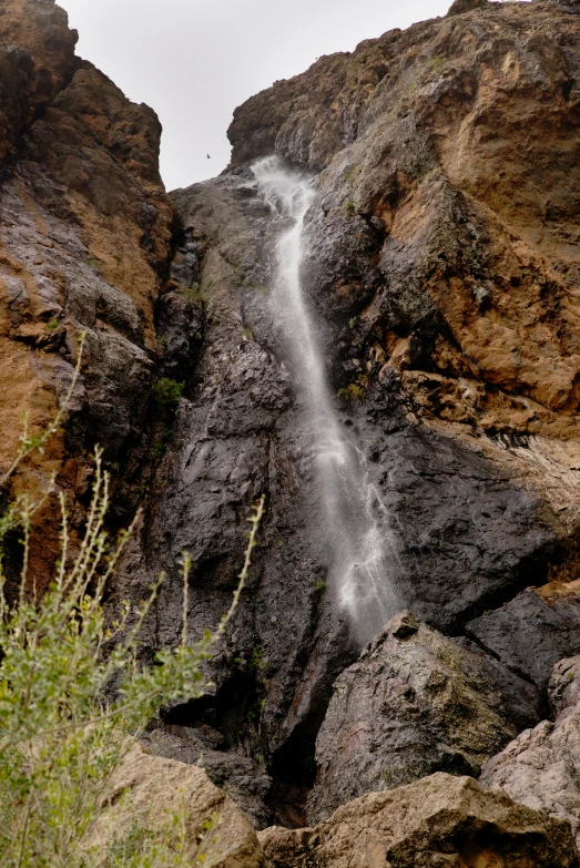 a small waterfall spouting from the side of a large rock formation