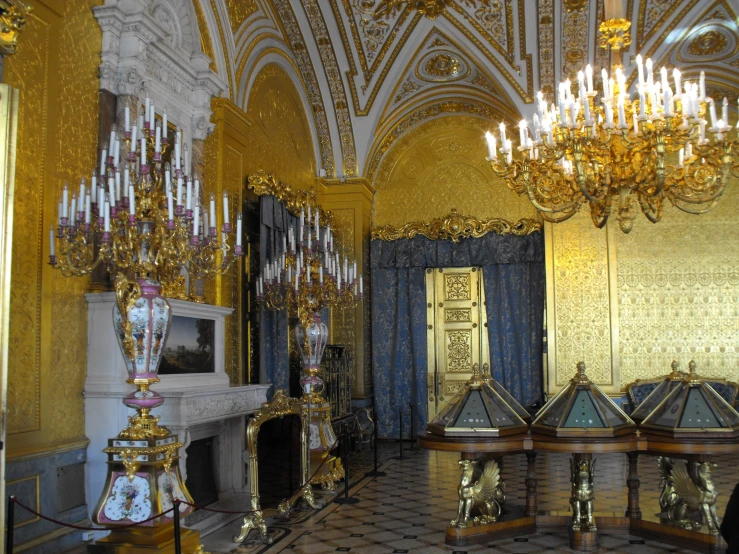 an elegantly designed room in gold color, with chandelier and fireplace