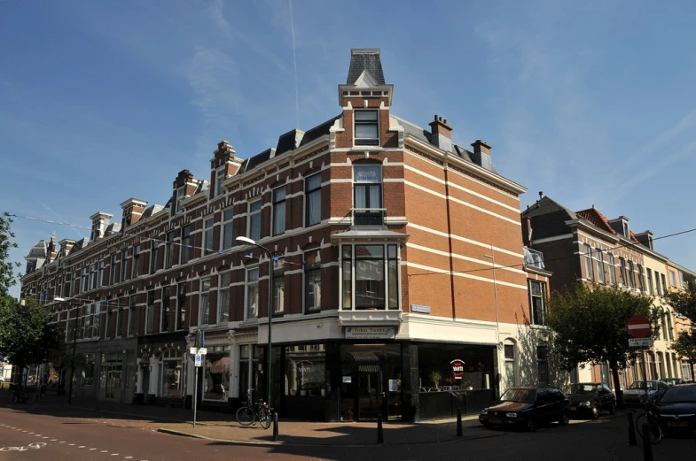 a street corner with a large building and cars parked nearby