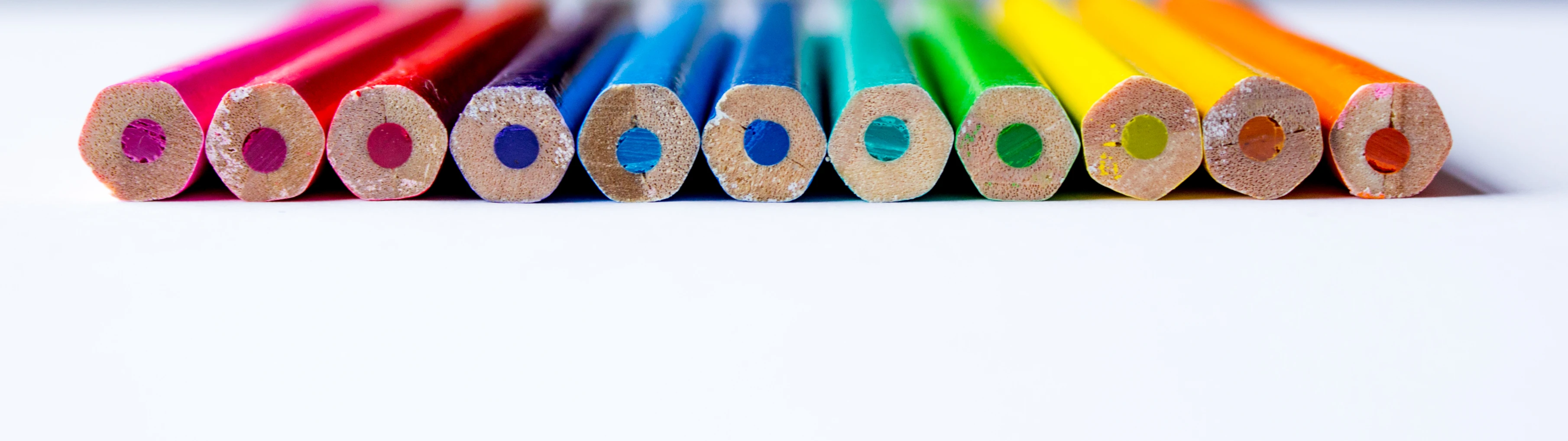 a row of colored pencils with a white background