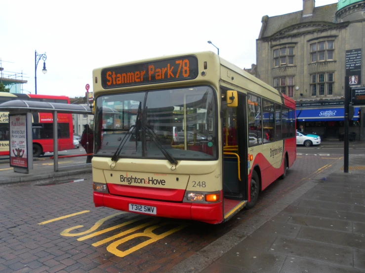 there is a yellow and red bus at the bus stop