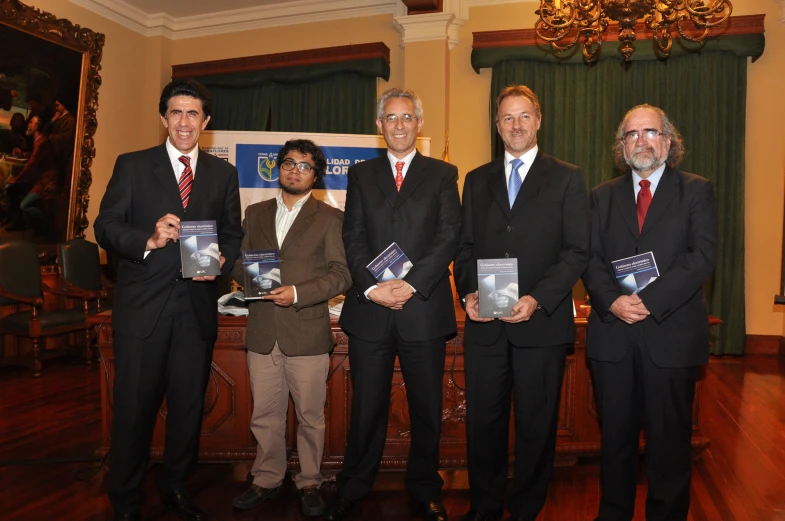 a group of people stand in front of a man holding several pamphlets