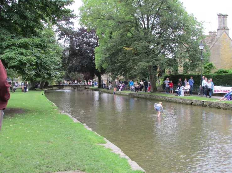 people are watching ducks swimming down a waterway