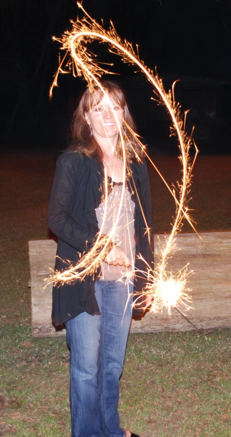 a woman standing on a bench and holding some sparklers