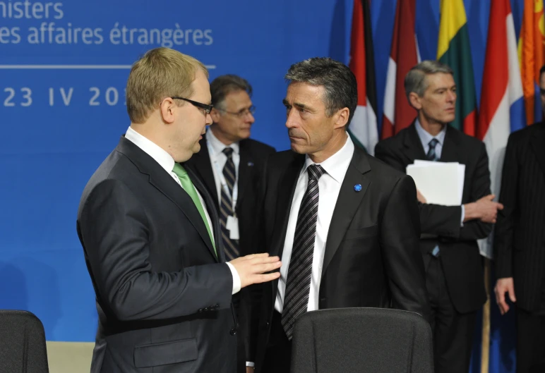 two men standing next to each other near flags