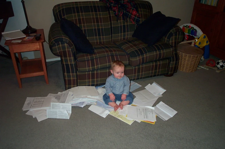 a toddler sitting on papers while playing with it