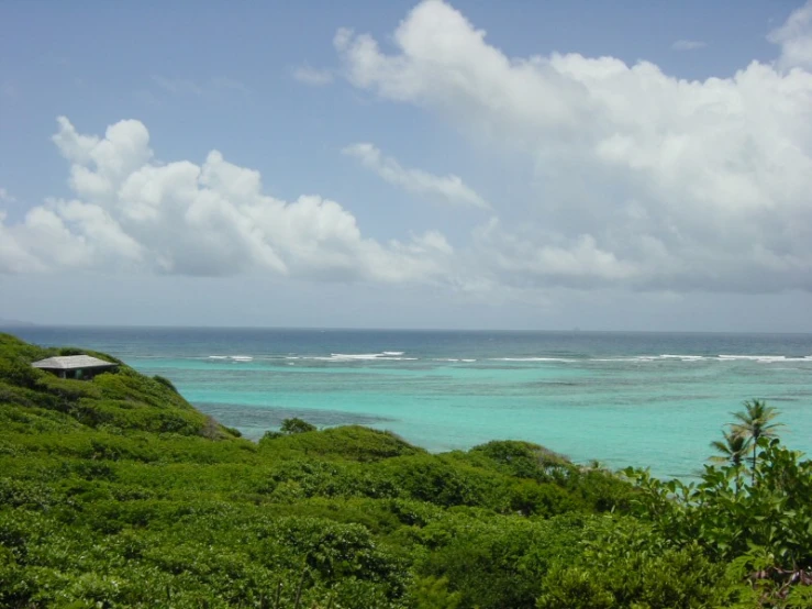 a large body of water sitting next to a lush green hillside