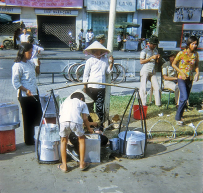 old picture of four people cleaning dishes off the street