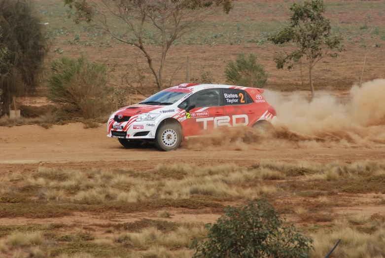 a white car driving on a dirt road through the desert